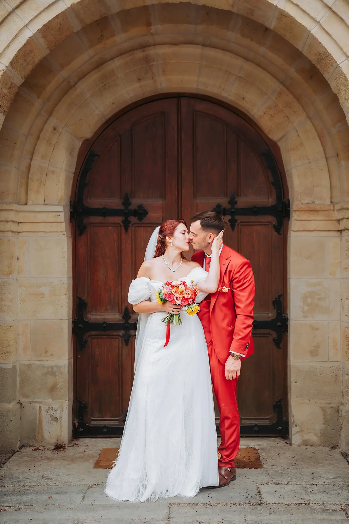 Aurélie & Jérémy 82 Mariés s'embrassant devant la porte en bois du Domaine de la Dame Blanche