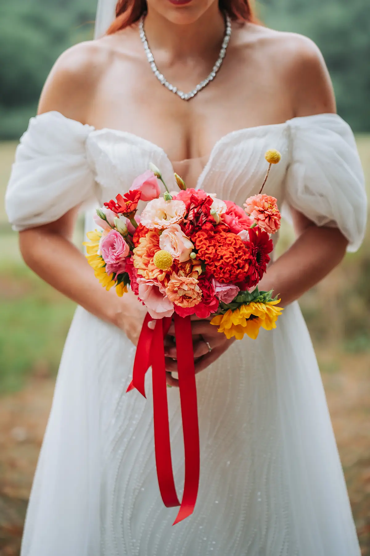 Aurélie & Jérémy 91 Mariée en robe blanche tenant un bouquet de fleurs aux tons rouges et jaunes