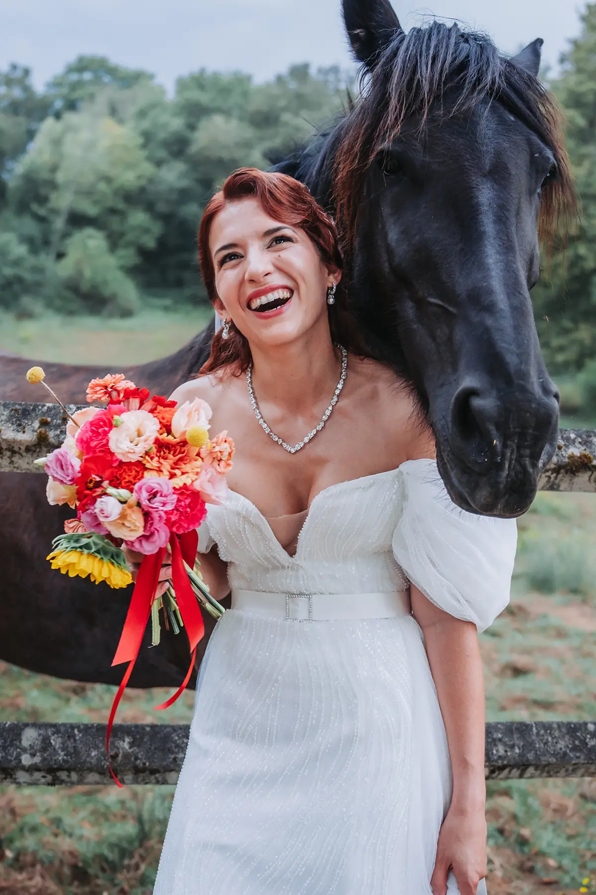 Aurélie & Jérémy 94 Mariée souriante posant avec un cheval noir au Domaine de la Dame Blanche à Grignols