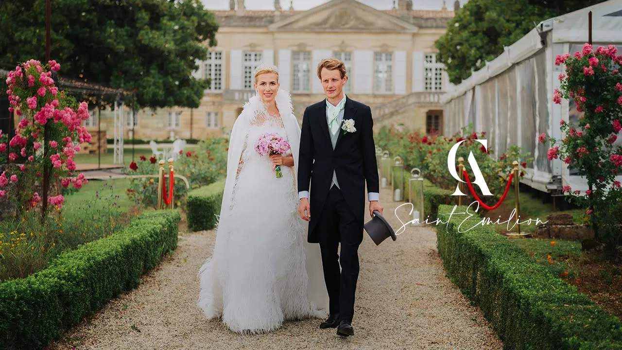 Film 7 Mariés marchant dans une allée bordée de rosiers devant un domaine à Saint-Émilion